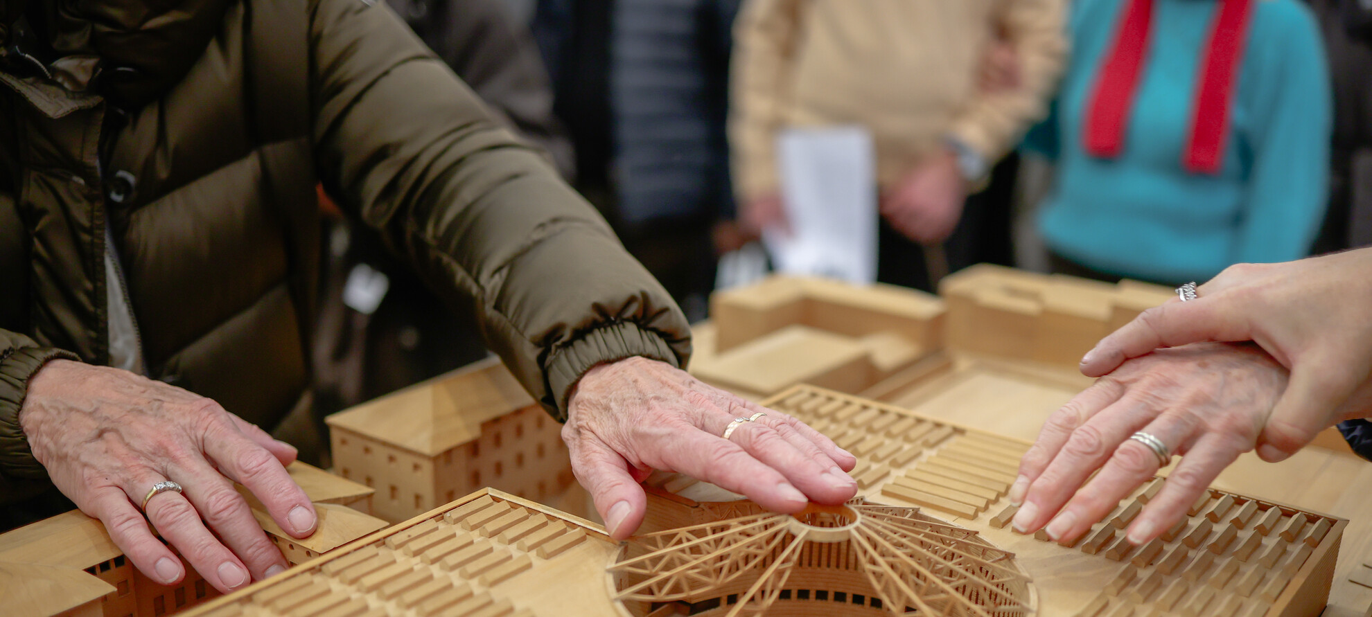 Dettaglio delle mani di due donne con disabilità visiva che esplorano il modellino tattile del MART. 