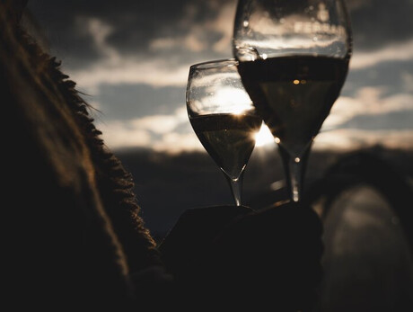 Two wine glasses at sunset with cloudy sky in the background